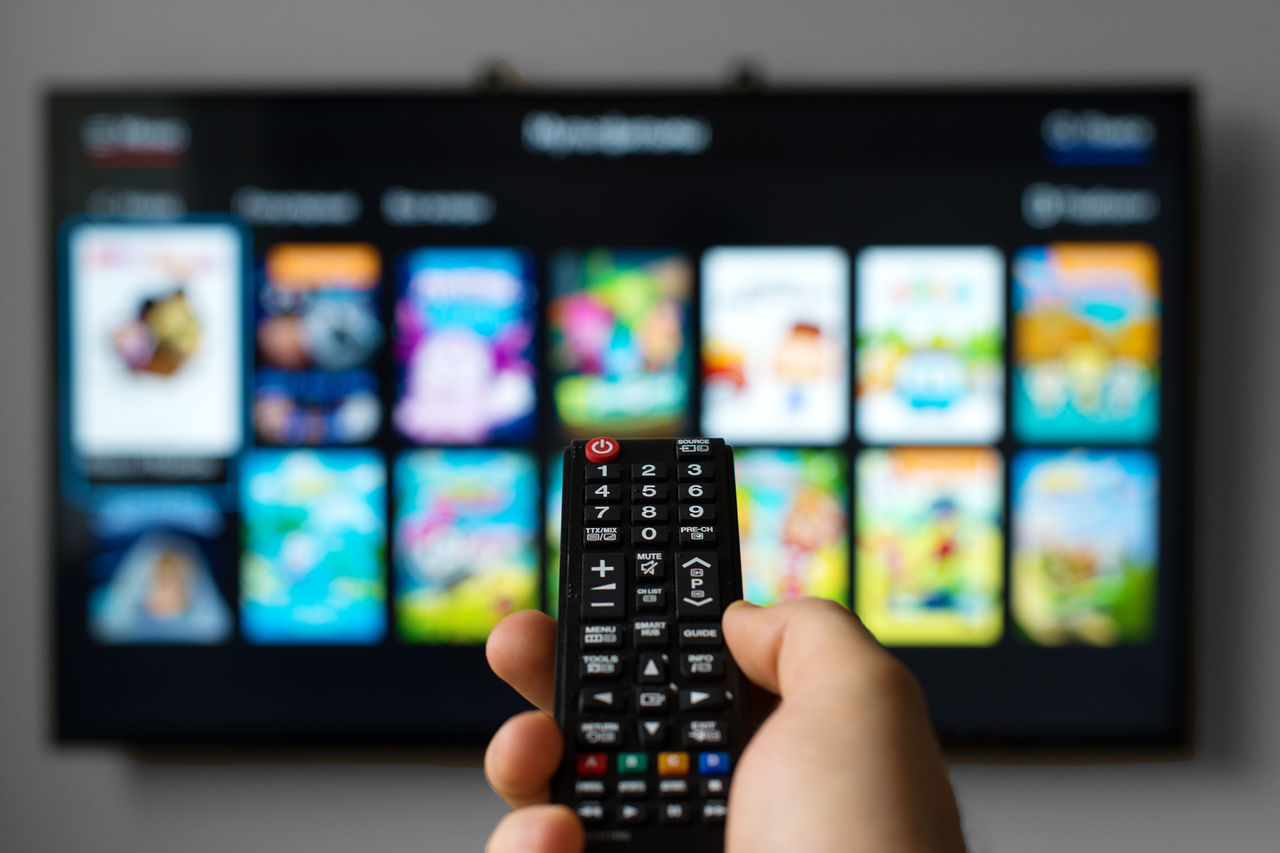 Male hand holding TV remote control