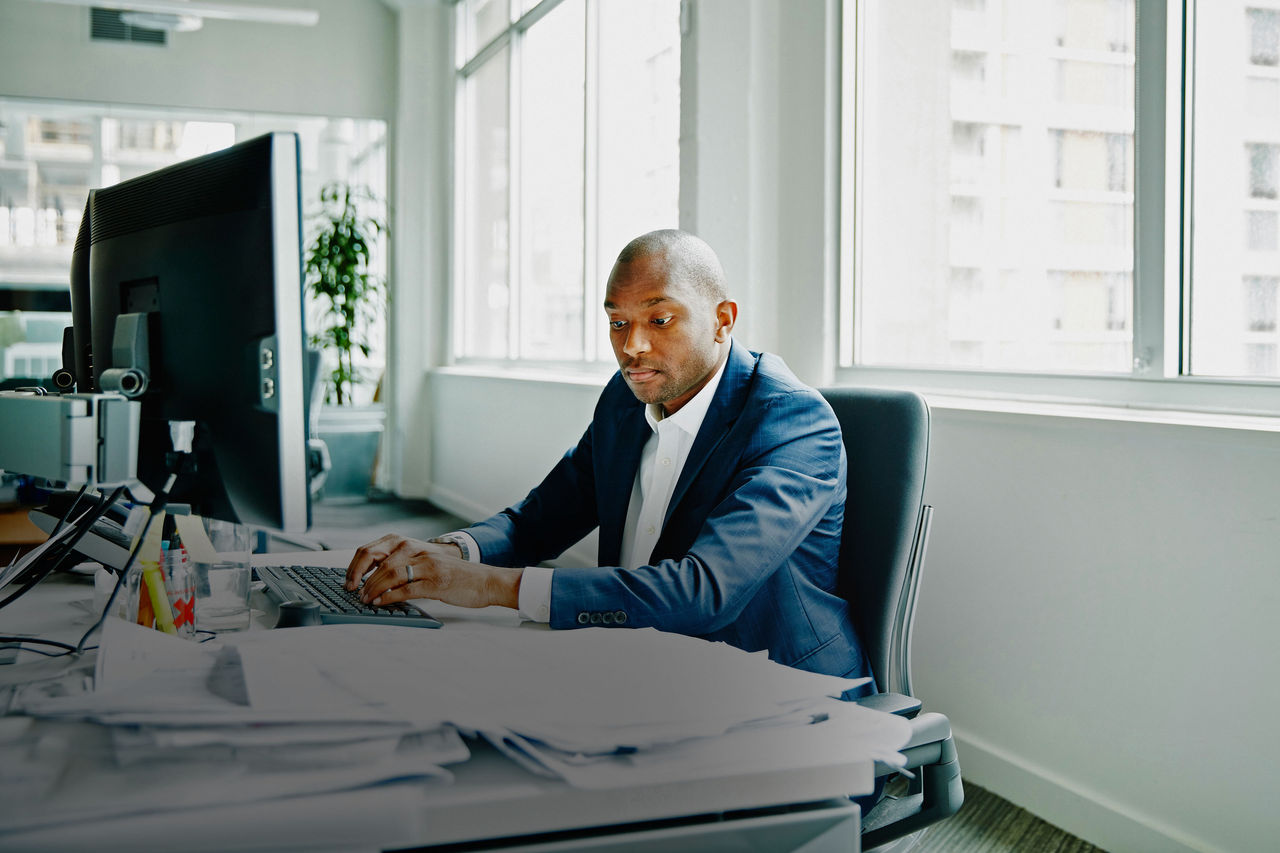 Businessman sitting at office workstation working on project on computer in office