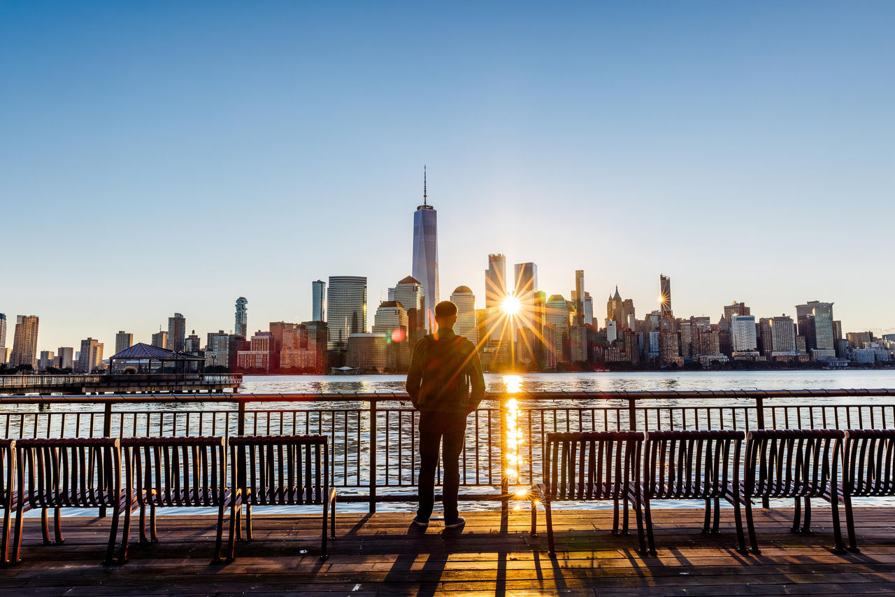 Rear view of a man looking at New York City skyline at sunrise, USA