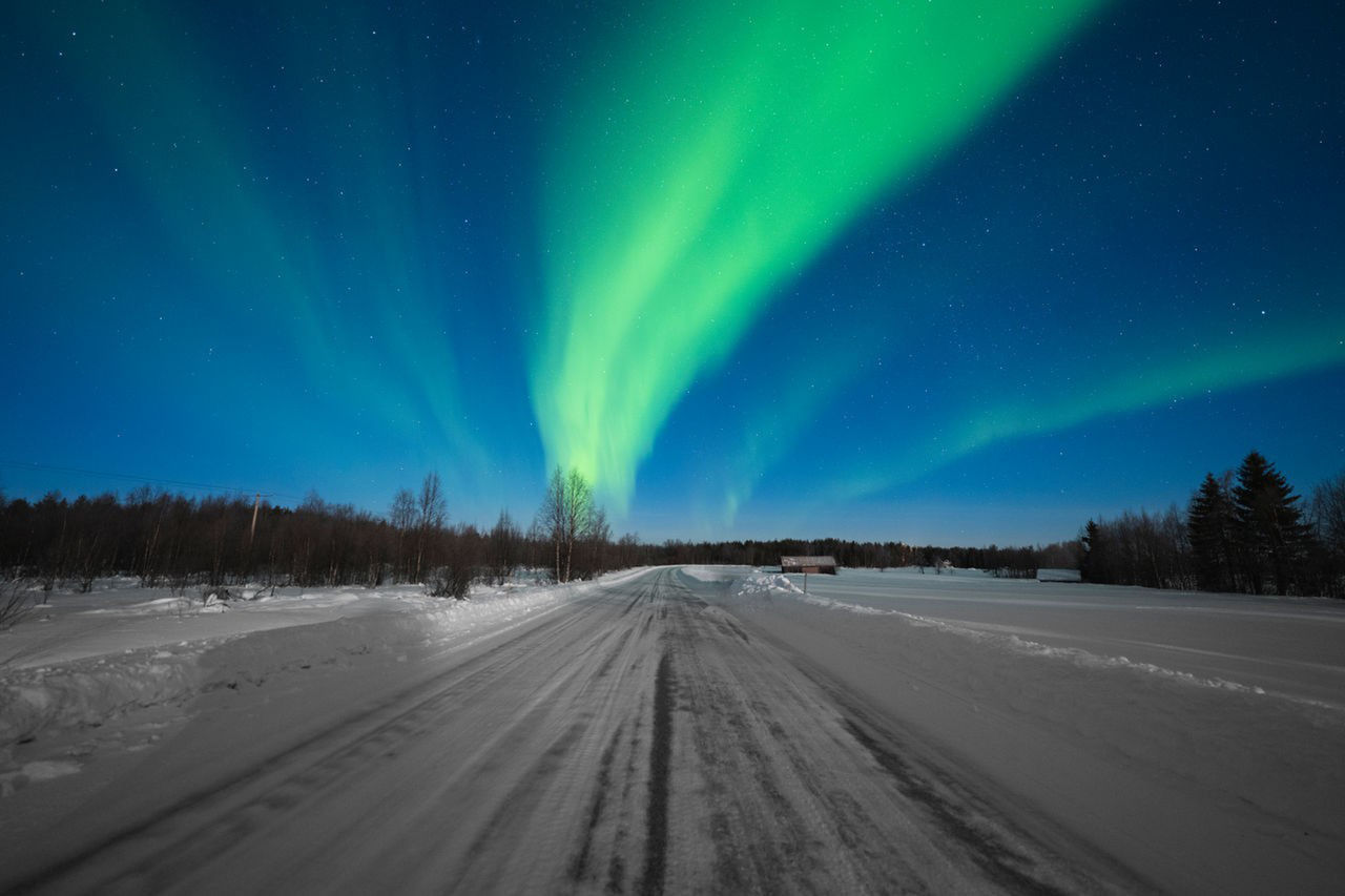 SaT use only Snowy winter road under Aurora Borealis