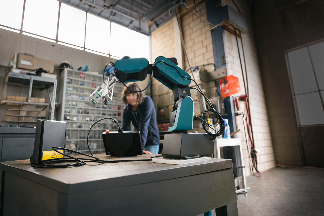 female technician programs a robot arm with a digital tablet