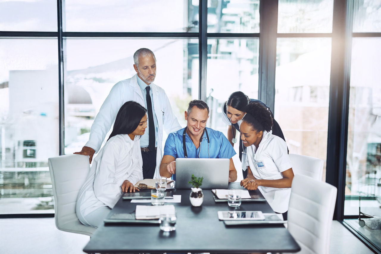 Doctor, diversity and laptop in team meeting for healthcare strategy, planning and collaboration in a hospital. Group of doctors, teamwork and discussion on computer technology with medical students.